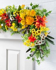 Artificial garland with orange and yellow flowers over a white door