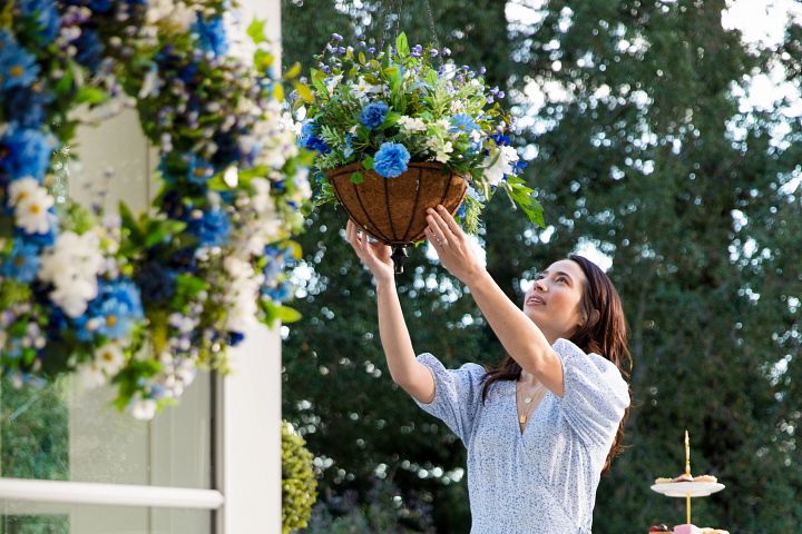 Woman hanging an artificial spring floral basket outdoors
