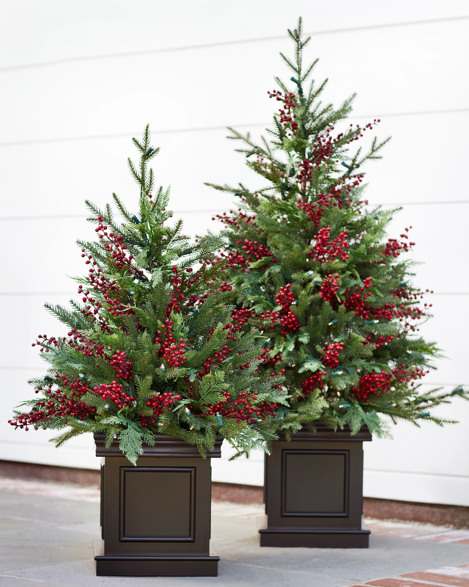 Pair of potted mini artificial Christmas trees with red berries and brown planters