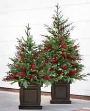 Pair of potted mini artificial Christmas trees with red berries and brown planters