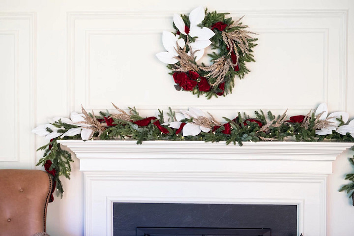 A fireplace mantel decorated with a wreath and garland in a Southern Christmas decorating theme