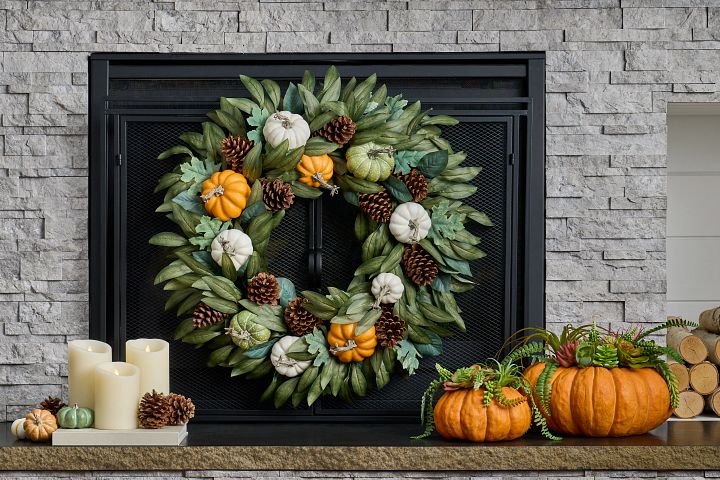 Fall fireplace décor idea with artificial autumn foliage and pumpkin decorations