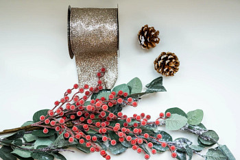 Flatlay of classic wreath decorations like champagne glittered Christmas tree ribbon, pinecones, frosted red berry picks, and frosted eucalyptus leaves