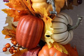 Close-up of artificial fall wreath with pumpkins, berries, and leaves