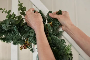Woman’s hands fluffing the foliage of artificial Christmas garland