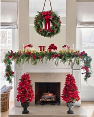 Holiday mantel décor idea with greenery, decorative gifts, and potted trees