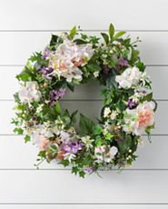 Artificial flower wreath with lavender and white blooms against a white background