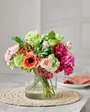 Artificial flower arrangement with hydrangeas and ranunculus in glass vase