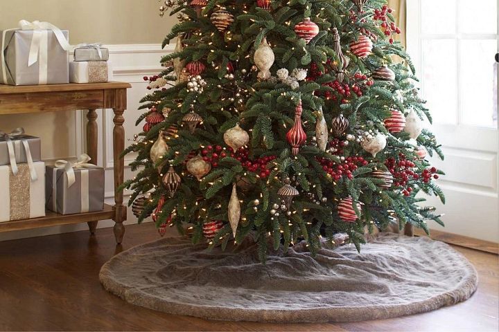 Image montrant la base d'un sapin de Noël décoré, recouvert d'un cache-pied en fausse fourrure
