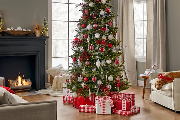 Pre-lit artificial Christmas tree decorated with red and white ornaments in a red metallic tree collar