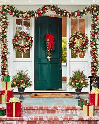 The façade of a house decorated with Christmas wreaths, garlands, and potted foliage
