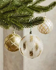 Closeup of white and gold Christmas tree ornaments on a tree