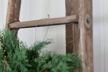 Artificial Christmas wreath hanging from a wire on a ladder