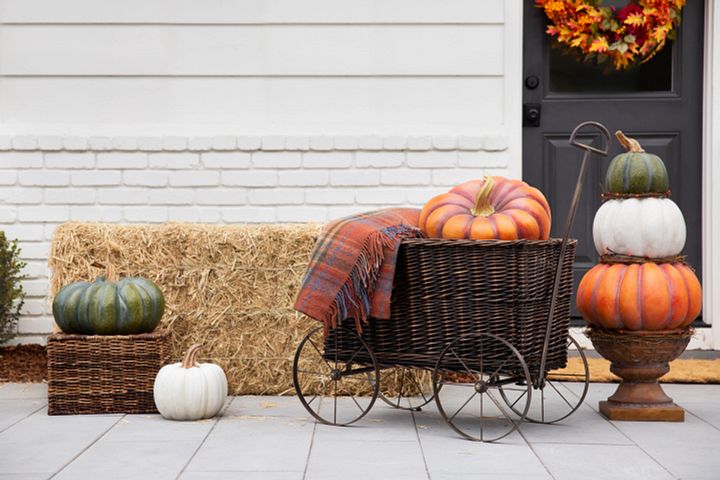 Stacked pumpkins next to a wheelbarrow containing a blanket and pumpkin