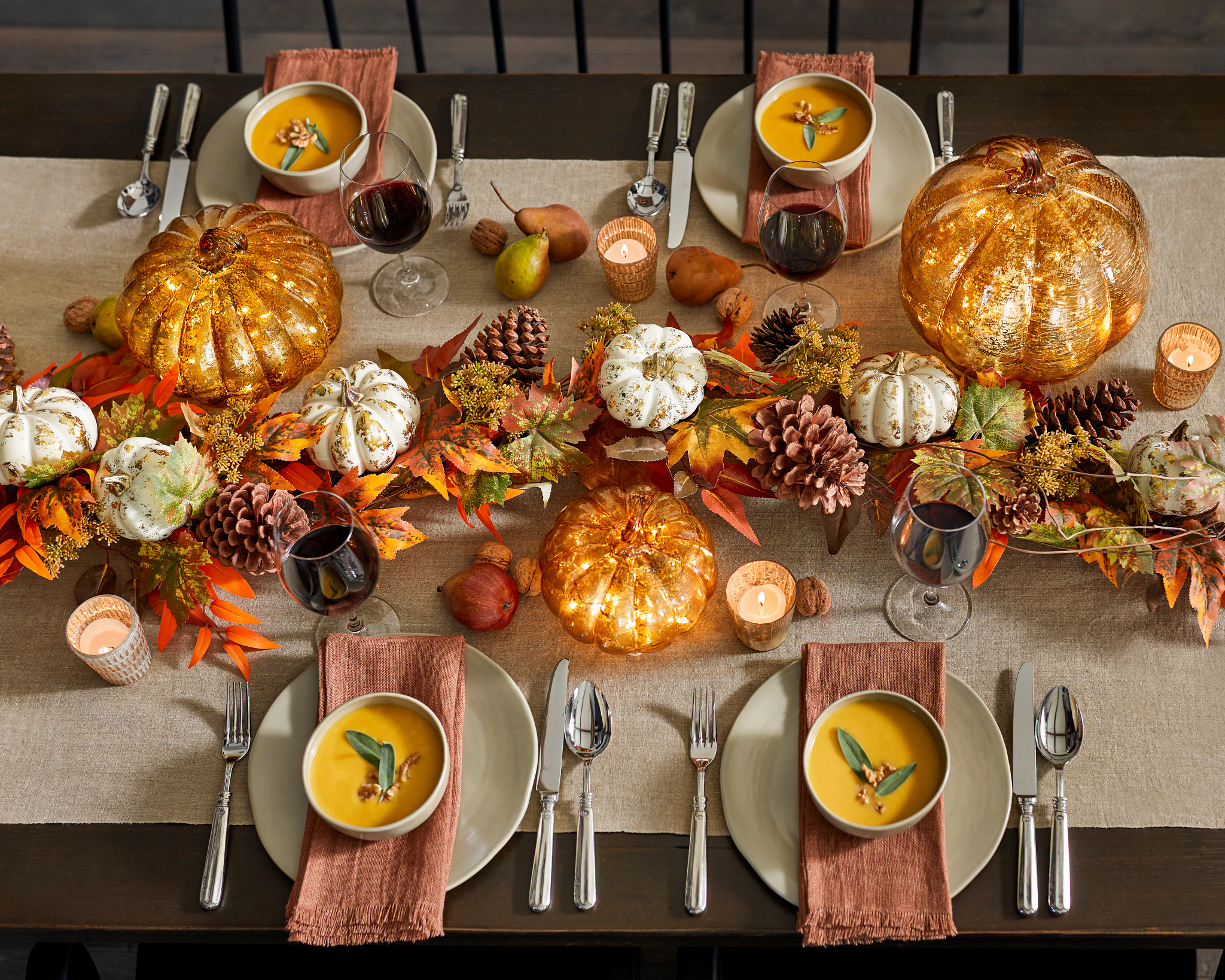  Thanksgiving tablescape with artificial fall garland, pumpkins, and place settings