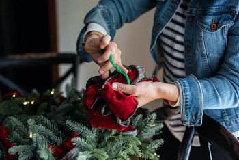 Hands tying a pipe cleaner to secure the rosette bow