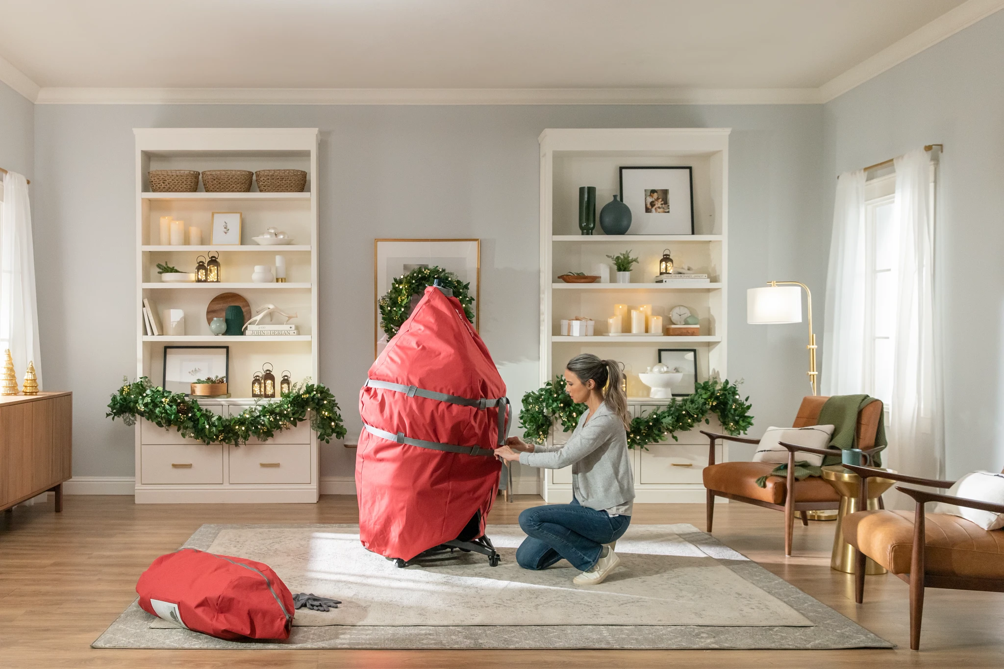 Woman storing her artificial Christmas tree in a red storage bag