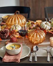 Tablescape with dinnerware, pumpkins, pinecones, and fall garland