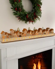 Wooden Christmas village Advent calendar on a white fireplace mantel