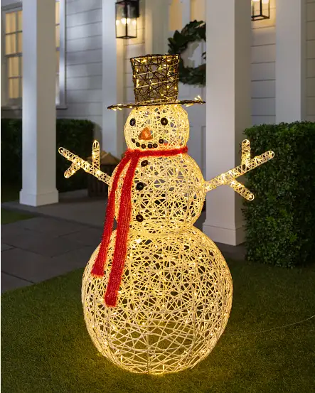 Beleuchtete Schneemann-Weihnachtsdekoration mit rotem Schal auf einem Vorgarten.