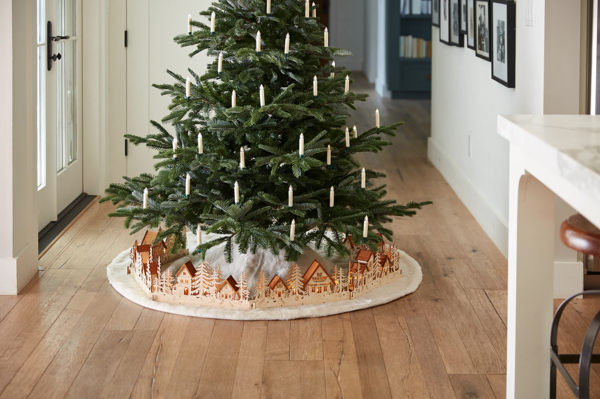 Artificial Christmas tree decorated with LED candles and Christmas village tree collar