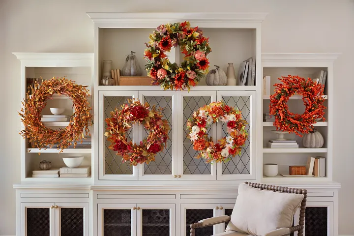Group of fall wreaths hanging on a white cabinet