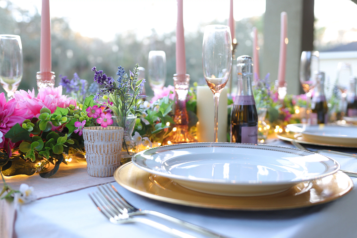 A table setup with wine bottles, flower garlands, and lights