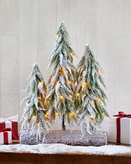 Artificial tabletop mini trees with faux snow on a console table