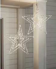 Lighted star-shaped outdoor Christmas décor hanging from a porch beam