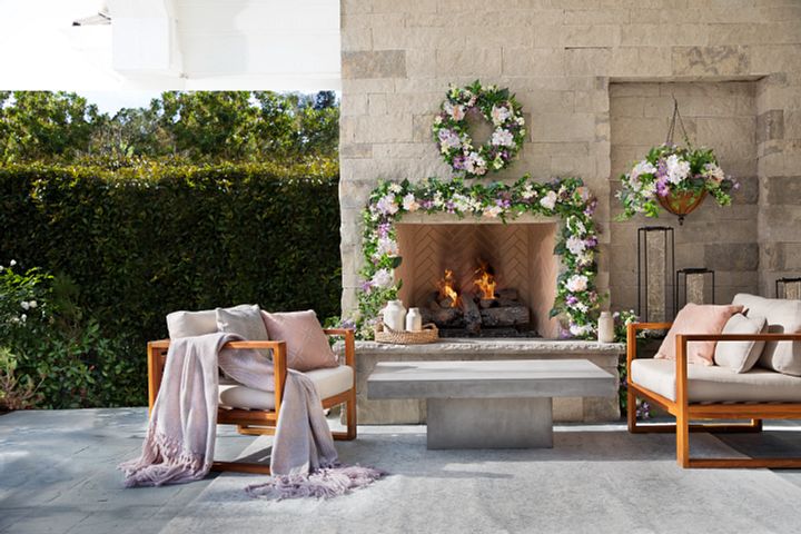 Outdoor seating area with fireplace decorated with spring wreath, garland, and hanging basket