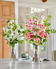 Artificial flower arrangements with white and pink cherry blossoms in clear glass vase