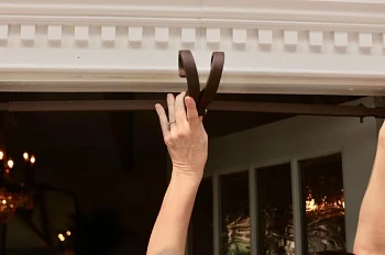 Pair of hands mounting a metal garland hanger over a door frame