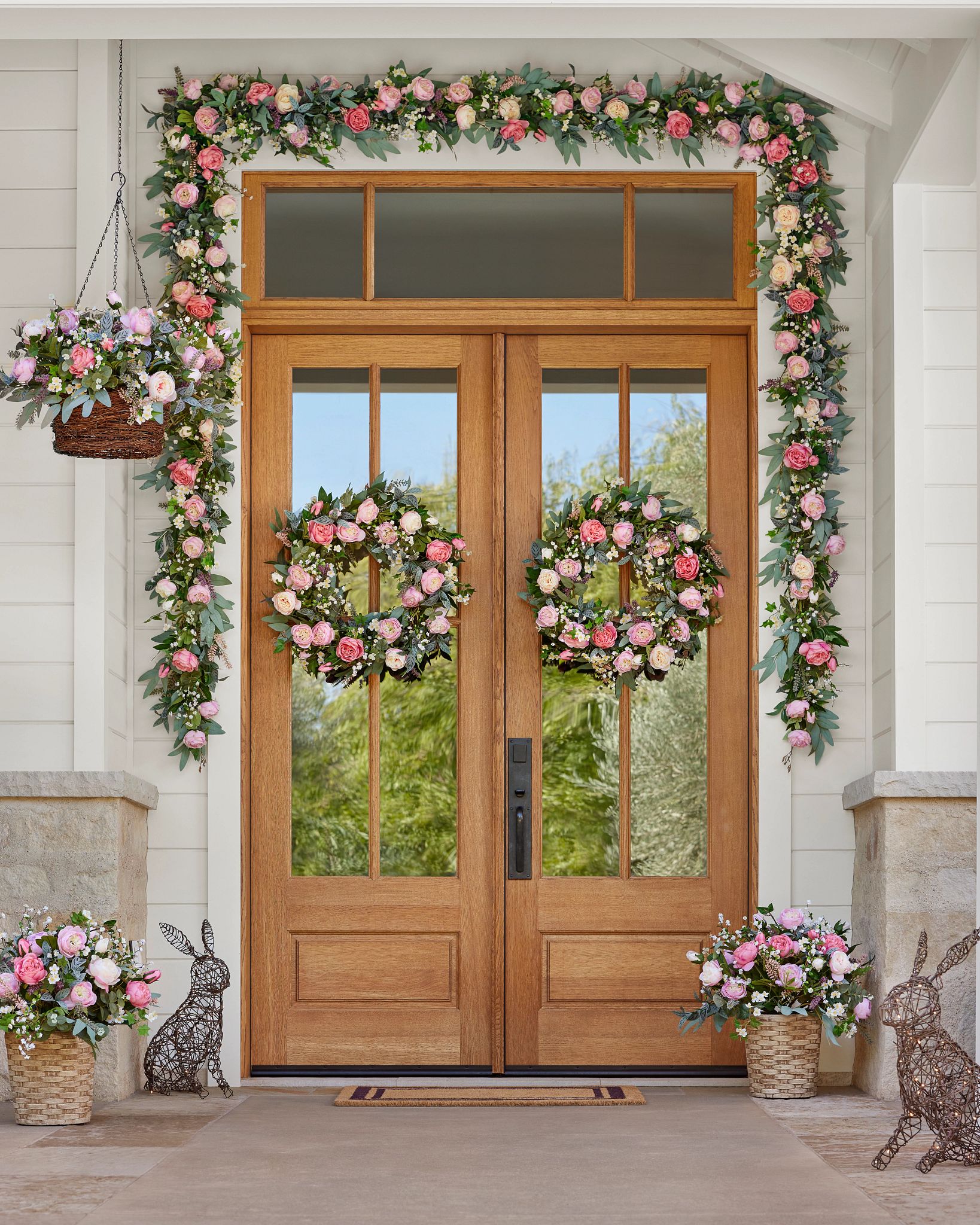 Front porch decorated with pink flower wreaths, garlands, and hanging baskets