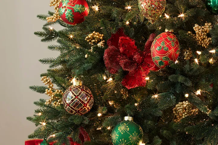 Pre-lit Christmas tree decorated with red, green, and gold ornaments and flower and berry picks