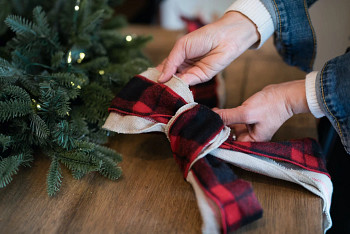 Hands pulling the sides of a looped Christmas tree ribbon