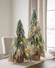 Set of frosted downswept tabletop Christmas trees on a wooden dining table