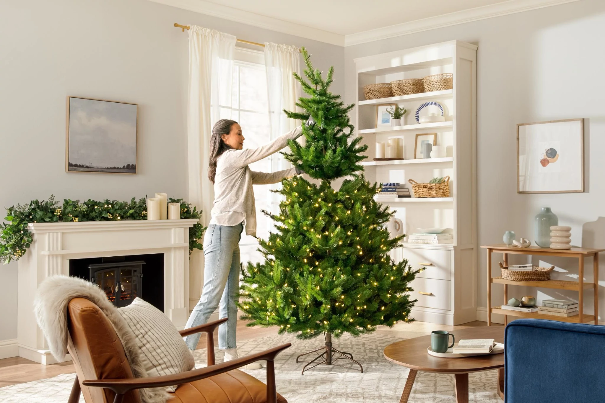 Woman in living room setting up a pre-lit artificial Christmas tree
