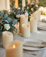 Flameless candles, foliage, plates, and utensils, on dining table