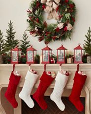 Red and white Christmas stockings hanging from lantern holders on the mantel