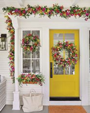 Yellow front door with artificial flower wreaths and garlands