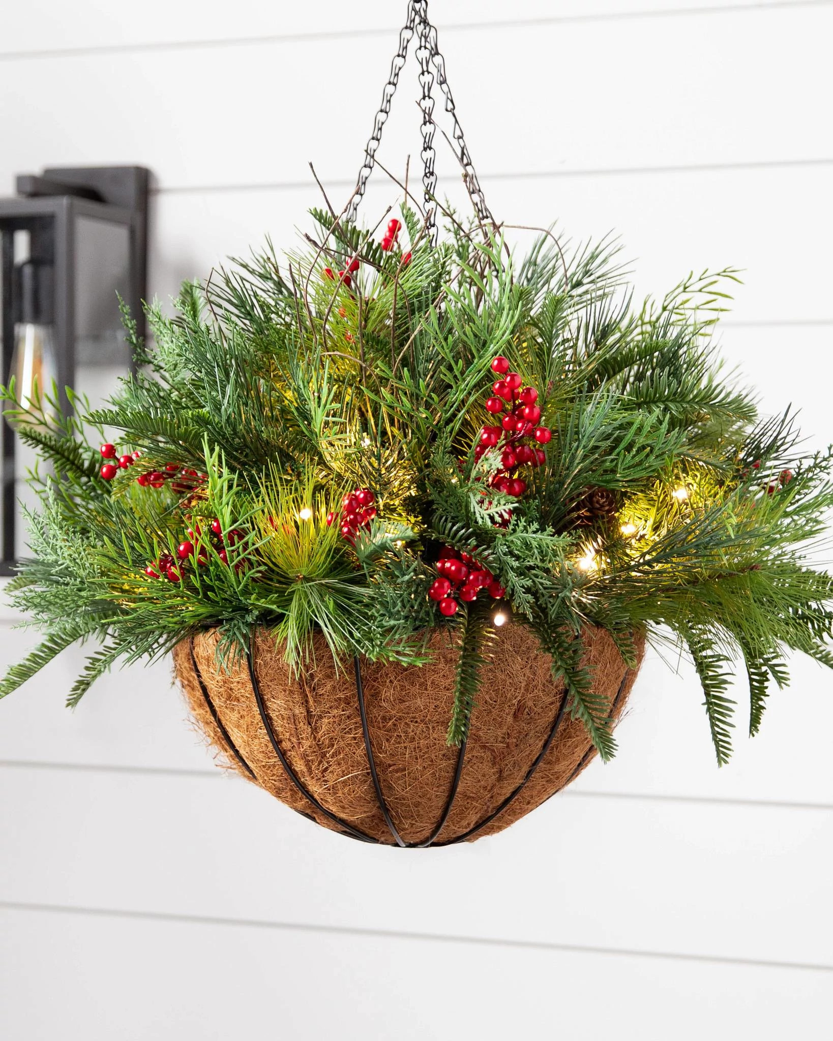 Artificial evergreens with red berries and pinecones in a hanging basket