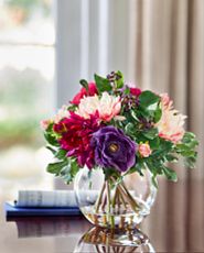 Artificial flower arrangement with dahlias in clear glass vase