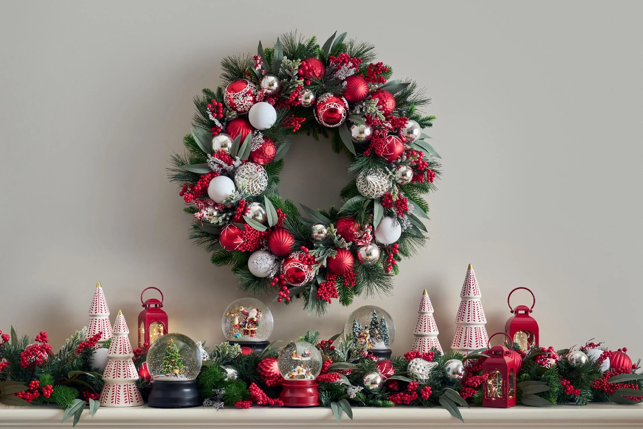 Mantle decorated Christmas wreath and garland with red and silver ornaments