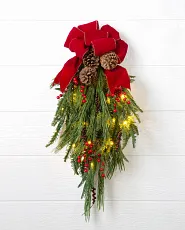 Künstliches Weihnachtsgesteck mit Kiefernzapfen, Beeren, Lichtern und einer roten Schleife