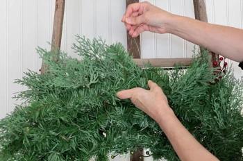 Pair of hands looping craft wire through an artificial Christmas wreath