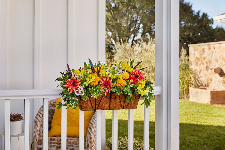 Artificial window flower box on white porch railing