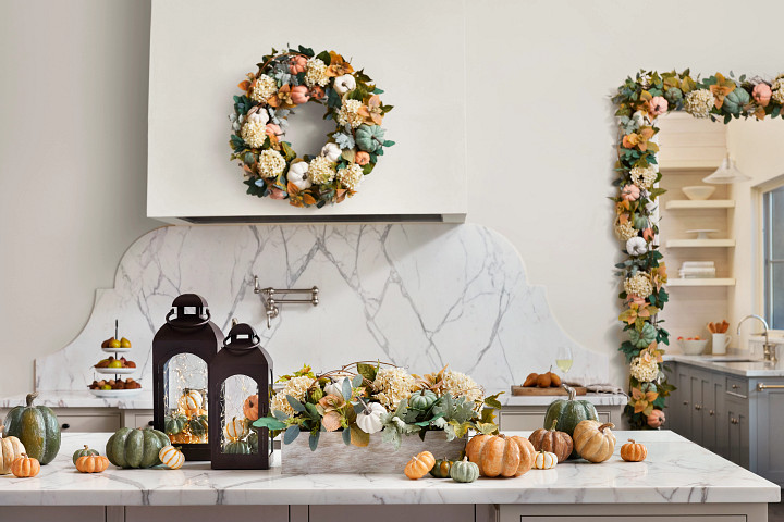 Minimalist kitchen decorated with fall greenery, pumpkins, and lanterns