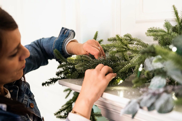 A woman fluffing a Christmas garland