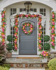 Gray front door decorated with artificial wreath and garlands with faux peonies and dahlias