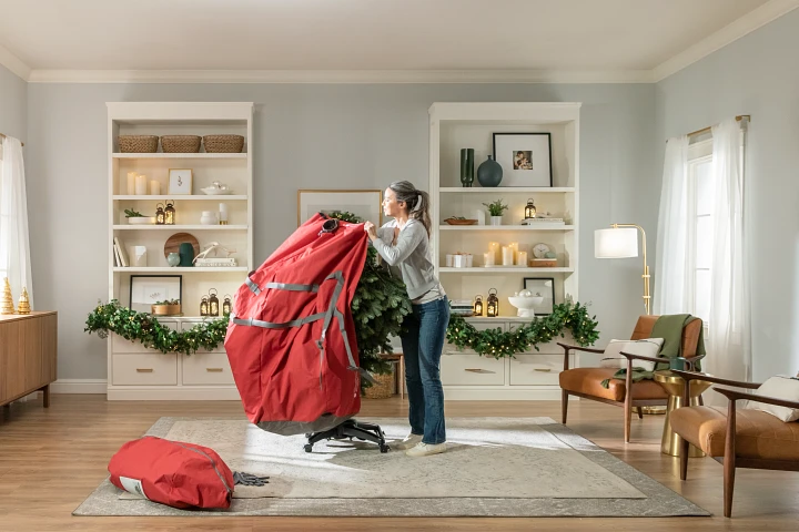 Woman packing her tree into a red Christmas tree storage bag